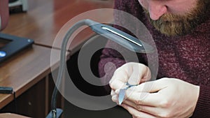 An elderly man sharpens a knife with a whetstone close-up