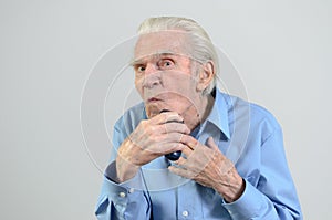 Elderly man shaving with a cordless electric razor