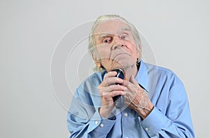 Elderly man shaving with a cordless electric razor