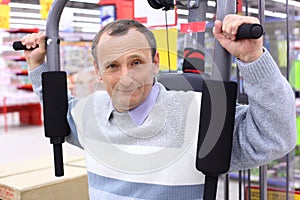 Elderly man in shop on sports exerciser photo