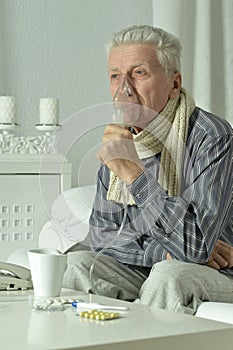 An elderly man is sick and uses an inhaler