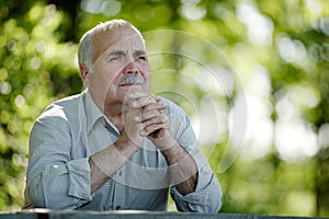 Elderly man sitting in the garden thinking