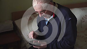 Elderly man sitting at home and using smart phone. Online delivery. Virtual medicine. News website. Connection with