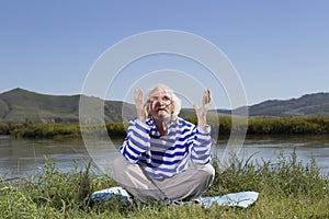 Elderly man sitting on a river bank