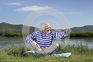 Elderly man sitting on a river bank