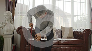 Elderly man sitting on sofa and pain his knee