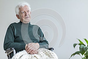 Elderly man sitting in a wheelchair and thinking about good times. Place your poster