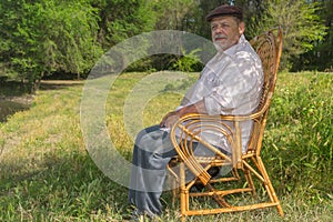 Elderly man sitting in a wicker chair