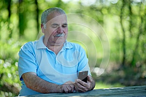 Elderly man smiling as he reads an sms