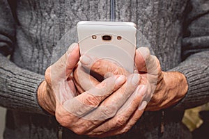 Elderly man standing with mobile phone in hand