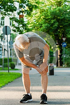 Elderly man suffering from knee pain during his jogging workout