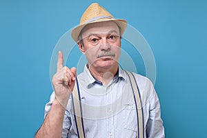 Elderly man in summer hat showing his finger up giving a good advice