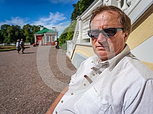 An elderly man in sunglasses resting in the city Park