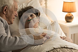 Elderly man supporting sick wife