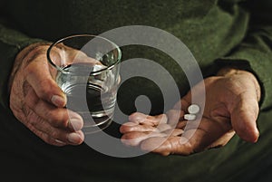 Elderly man taking his medication, two tablets.