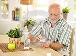 Elderly man taking pill at home photo