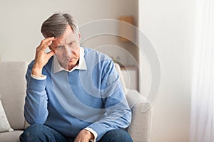 Elderly Man Thinking About Loneliness Sitting On Couch At Home photo