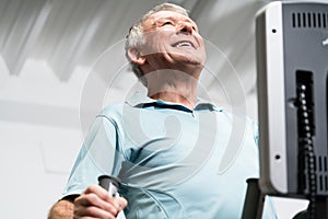 Elderly man training on cross trainer at the gym