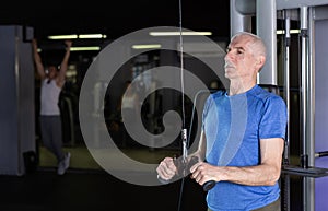 Elderly man training with straps in gym