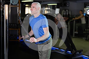 Elderly man training with straps in gym