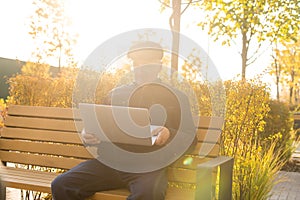 Elderly man use laptop in the park. Handsome senior man in glasses work outside.