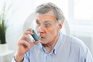 Elderly man using asthma inhaler for allergies