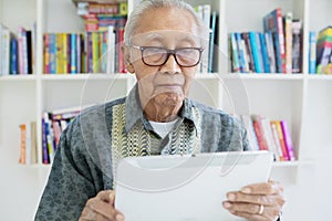 Elderly man using digital tablet in the library