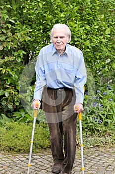 Elderly man using forearm crutches to walk
