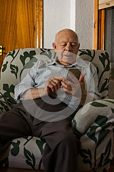 Elderly man is using his smartphone at home