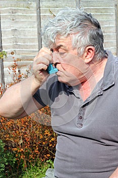 Elderly man using inhaler.