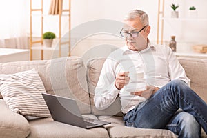Elderly Man Using Laptop Computer And Having Coffee