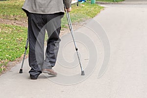 an elderly man walking on crutches on the street