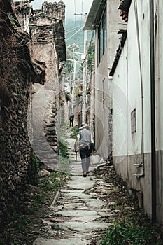 Elderly man walking on a deserted, rural road in Southern China