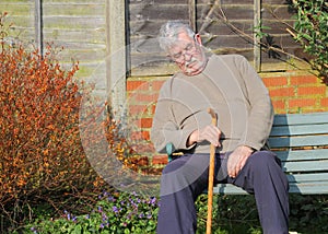 Elderly man with walking stick asleep.