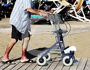 Elderly man walking with Walker on the beach