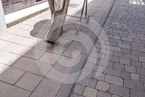 Elderly man walks by lowered sidewalk with walker