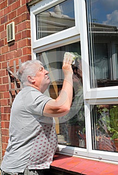 Elderly man washing or cleaning windows.