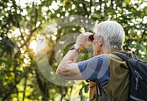 Elderly man watching birds with binoculars