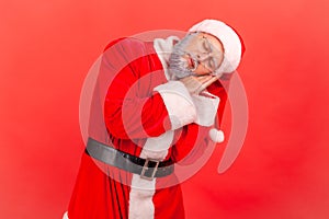 Elderly man wearing santa claus costume sleeping laying down on her palms and smiling pleased