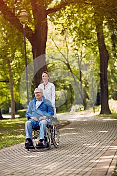 Elderly man on wheelchair with nurse outdoor