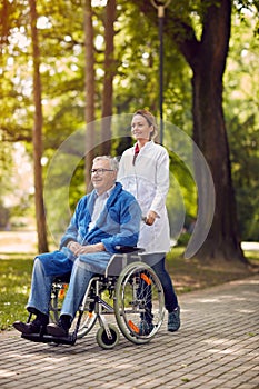 Elderly man on wheelchair with nurse outdoor