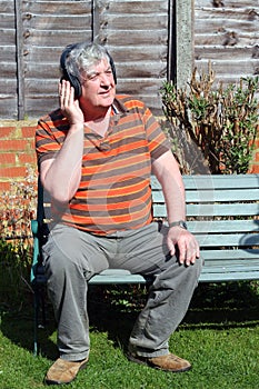 An elderly man with wireless headphones.