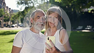 Elderly Man And Woman In The Park After Fitness Take Pictures Of Themselves On The Phone.