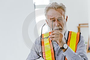 An elderly man worker removed glasses because of eyes irritation or stress from hard working