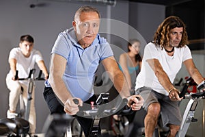 Elderly man working out on stationary bicycle in gym
