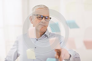 Elderly manager putting sticky notes on window