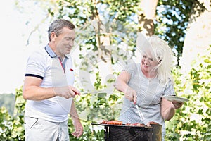 Elderly marriage grilling meat together.