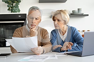 Elderly married couple looking at documents carefully