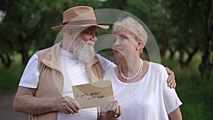 An elderly married couple looks at each other and talks, holding a sign with the inscription it gets better with age