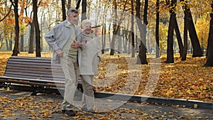 Elderly married couple walking in autumn park old woman holding husband hand enjoy conversation outdoors family long